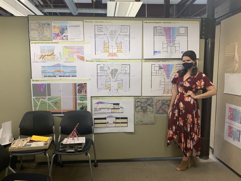 Early Drexel Pinup at Community Studio - Katie in a mask in front of a wall of interiors drawings