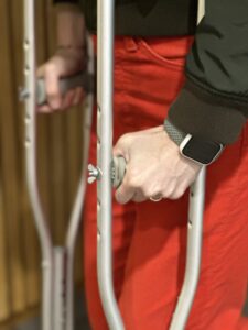 hands grip the handles of crutches
