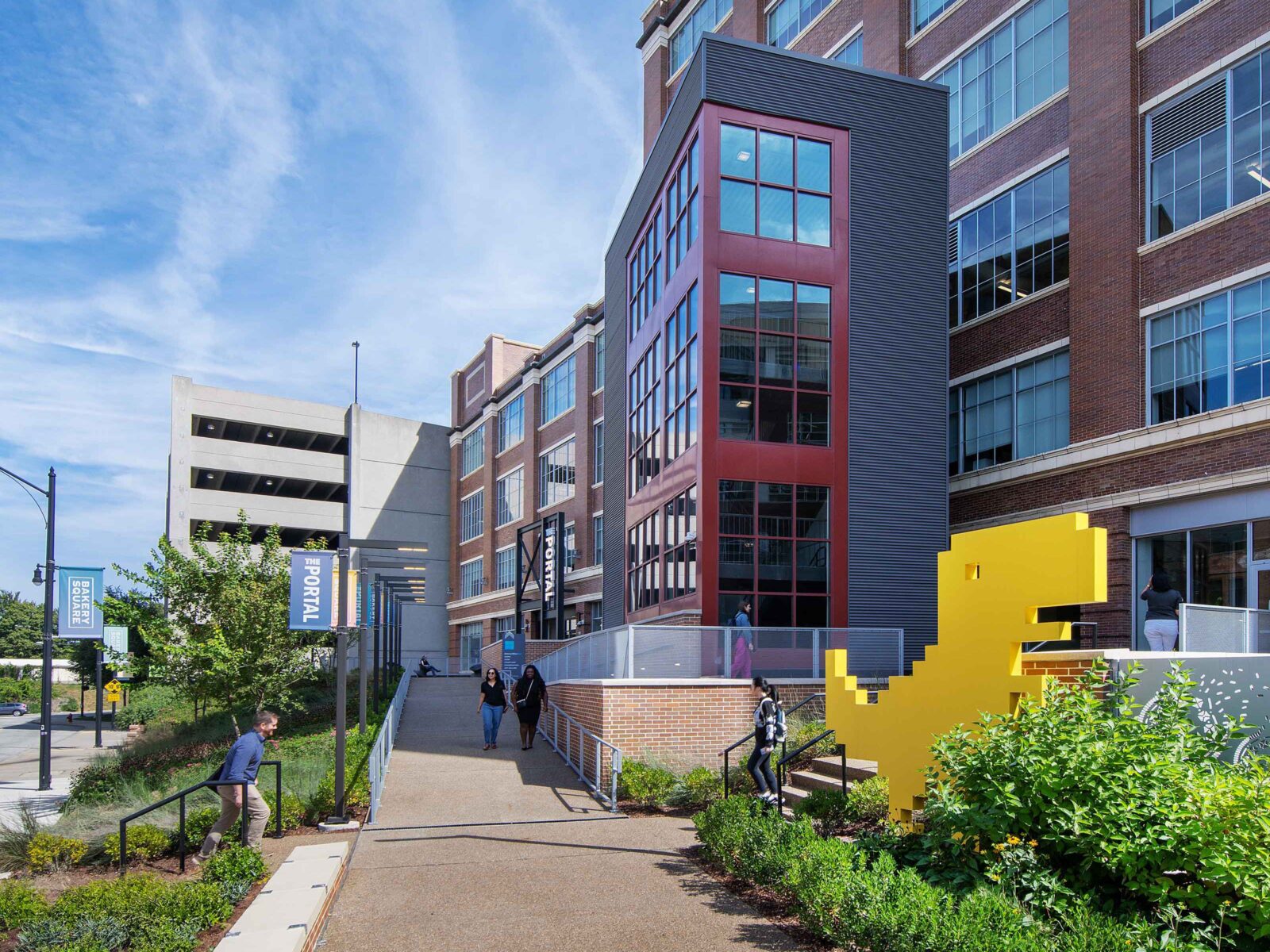 The connection to Larimer is flanked by lush plantings and a yellow Dino that pays homage to businesses at Bakery Square